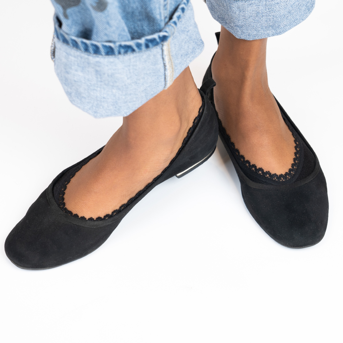 Close-up of woman wearing black low-show no-slip socks in black flats with cuffed jeans, showing elegant lace trim and full topline coverage.