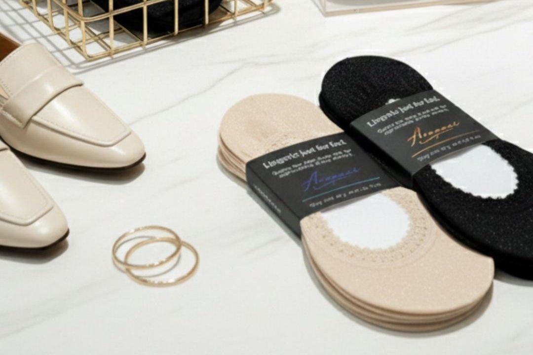 Arnacci lingerie-inspired low-cut footie socks displayed in a boutique retail setting, featuring black and sand shimmer no-show footies with non-slip design, packaged and merchandised for wholesale stores.