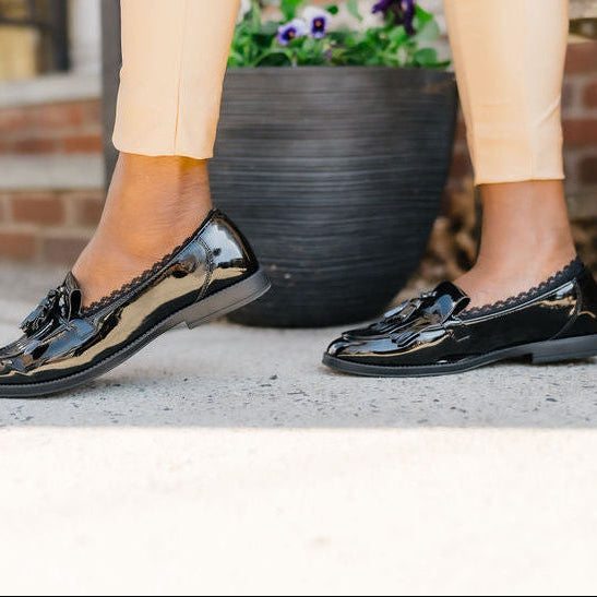 Side view of black woman wearing black loafers with Arbella Style footie peeking out - no-slip sock design