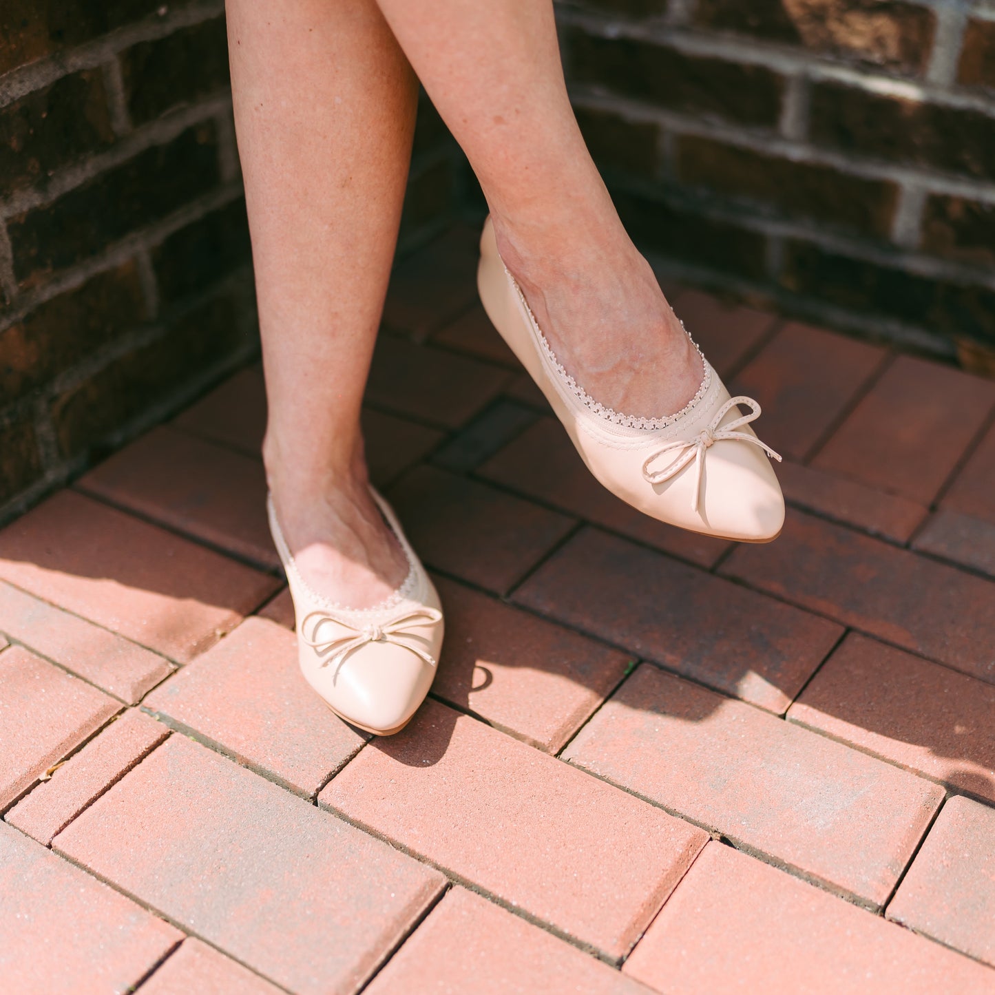 White woman with legs crossed wearing nude footie with cut-out ballerina flat - Arnacci barely-there socks